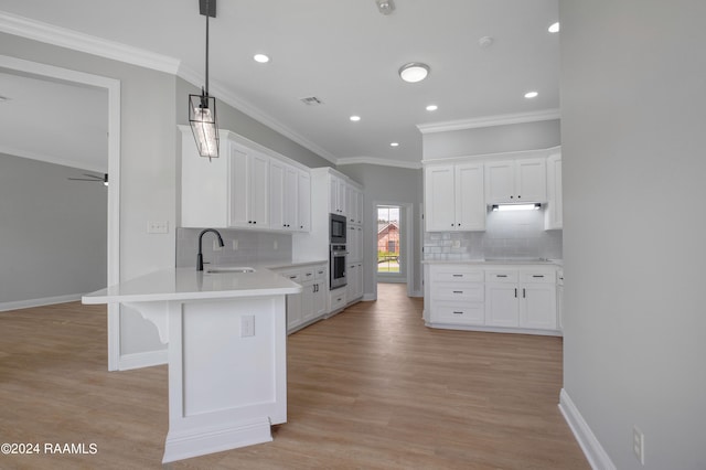 kitchen with stainless steel oven, light hardwood / wood-style flooring, decorative light fixtures, and tasteful backsplash