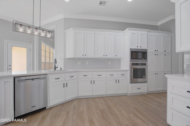 kitchen with appliances with stainless steel finishes, white cabinets, sink, pendant lighting, and light wood-type flooring