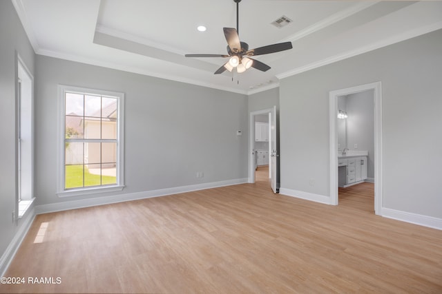 unfurnished bedroom with light wood-type flooring, ceiling fan, ensuite bathroom, a raised ceiling, and ornamental molding