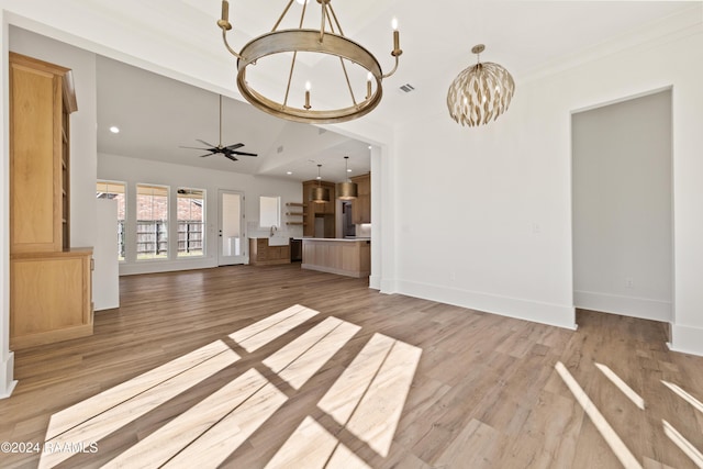 unfurnished living room with ceiling fan with notable chandelier, wood-type flooring, and high vaulted ceiling