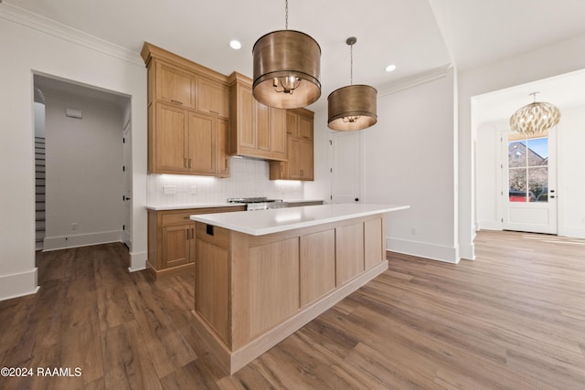 kitchen featuring pendant lighting, decorative backsplash, hardwood / wood-style flooring, ornamental molding, and a center island