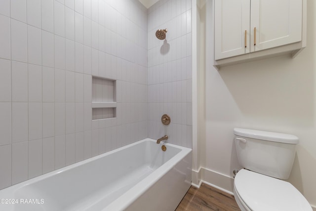 bathroom featuring tiled shower / bath, hardwood / wood-style floors, and toilet