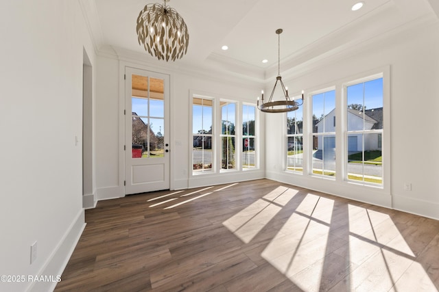 unfurnished dining area featuring crown molding, dark hardwood / wood-style floors, a raised ceiling, and a notable chandelier