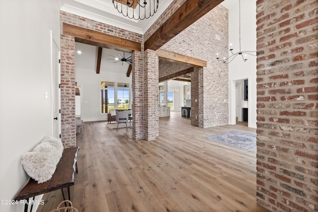 interior space featuring beamed ceiling, a high ceiling, hardwood / wood-style floors, and ceiling fan with notable chandelier