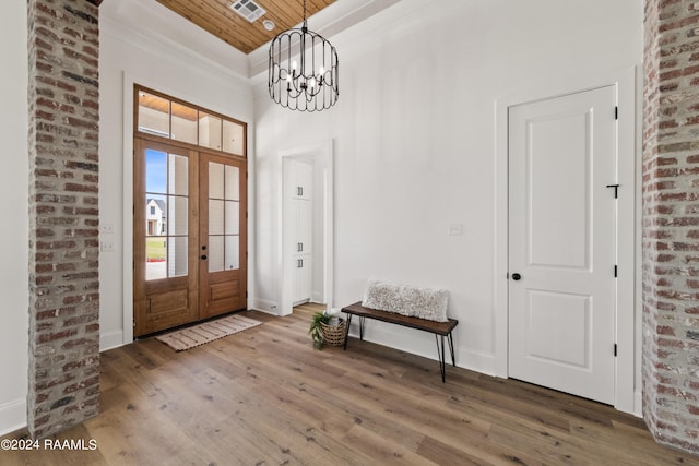 foyer entrance featuring french doors, a chandelier, wood ceiling, hardwood / wood-style floors, and brick wall