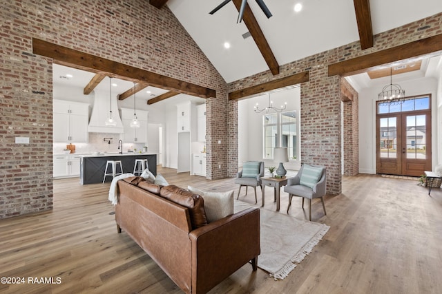 living room featuring high vaulted ceiling, light hardwood / wood-style flooring, brick wall, and beamed ceiling