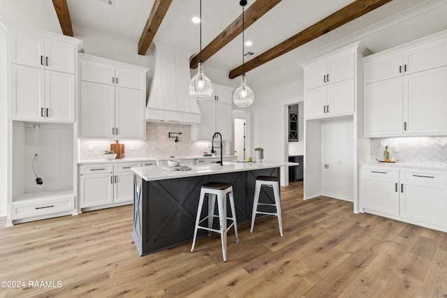 kitchen featuring beamed ceiling, white cabinetry, backsplash, and light hardwood / wood-style floors