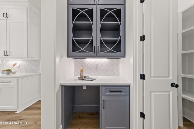 bar with gray cabinetry, backsplash, white cabinetry, and light hardwood / wood-style floors