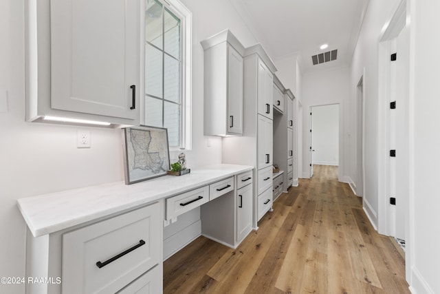 interior space featuring light hardwood / wood-style flooring, light stone countertops, ornamental molding, and a wealth of natural light