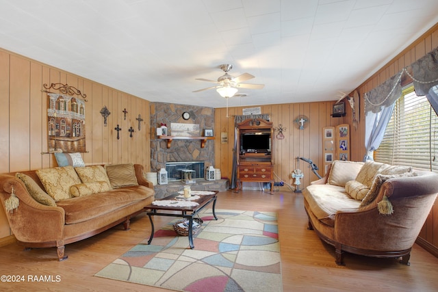 living room featuring wood walls, ceiling fan, and light wood-type flooring