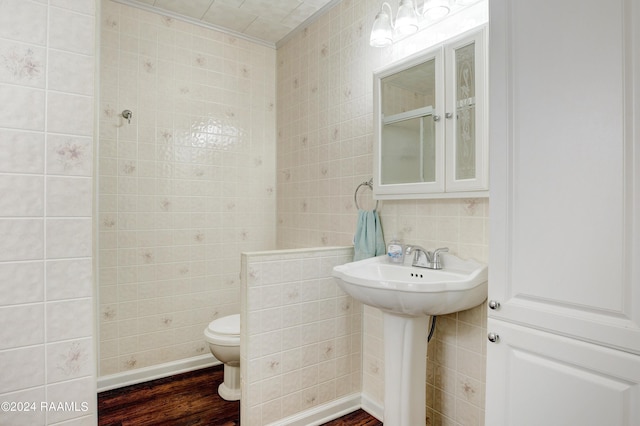 bathroom featuring wood-type flooring, toilet, and tile walls