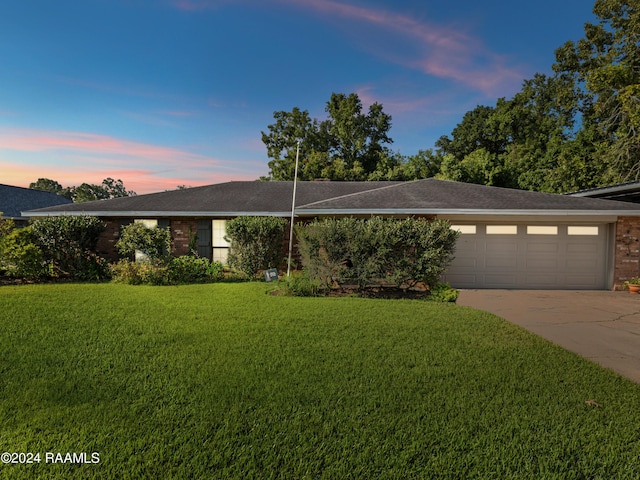 single story home with a garage and a lawn