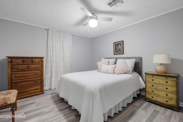 bedroom featuring ceiling fan, a textured ceiling, crown molding, and light hardwood / wood-style flooring