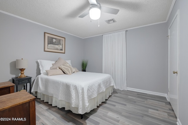 bedroom featuring crown molding, a textured ceiling, light hardwood / wood-style flooring, and ceiling fan