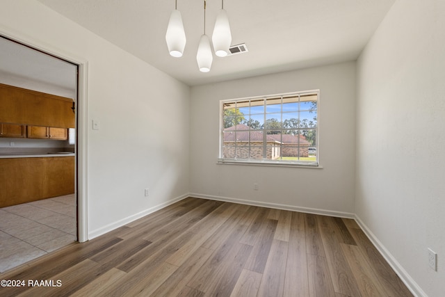 spare room featuring wood-type flooring and a notable chandelier