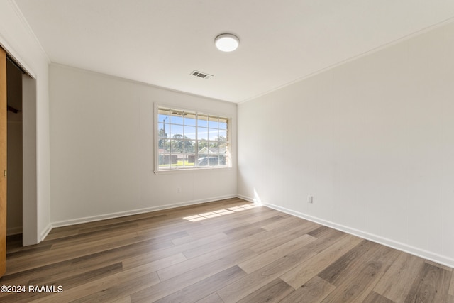 spare room featuring hardwood / wood-style flooring and ornamental molding