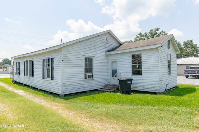 rear view of property with cooling unit and a lawn