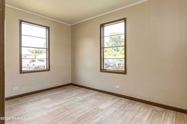 spare room featuring light wood-type flooring, plenty of natural light, and crown molding