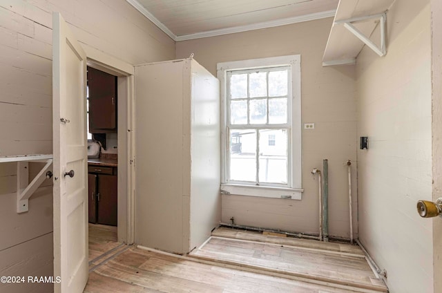 clothes washing area with light hardwood / wood-style flooring and crown molding