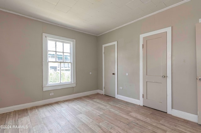 unfurnished bedroom featuring crown molding and light wood-type flooring