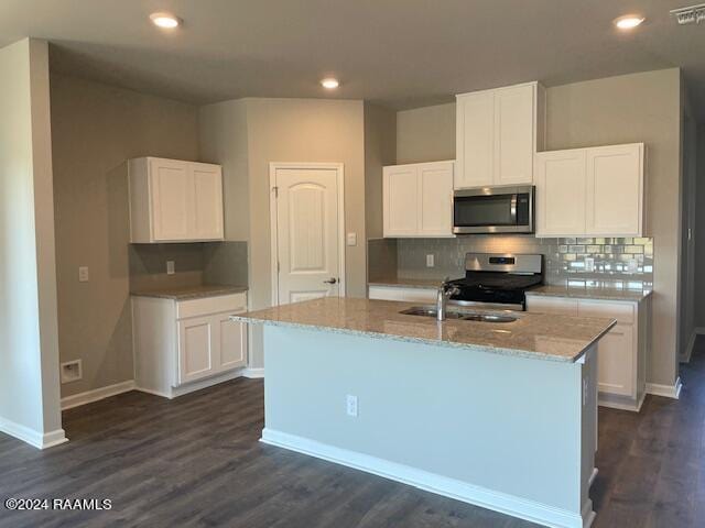 kitchen featuring appliances with stainless steel finishes, a kitchen island with sink, white cabinets, and dark hardwood / wood-style flooring