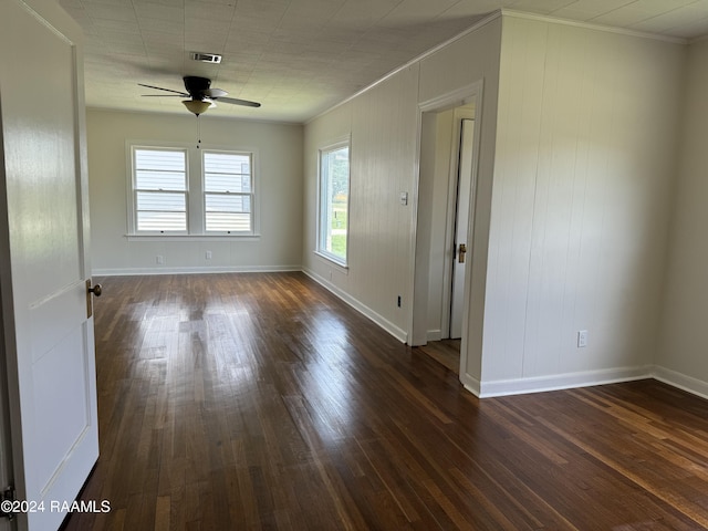 spare room with dark wood-style floors, ornamental molding, a ceiling fan, and baseboards