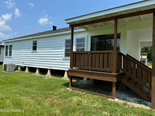 back of house with cooling unit, a wooden deck, and a lawn