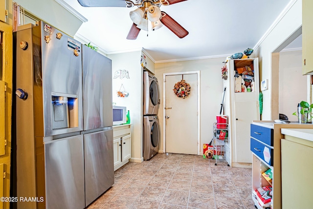 kitchen featuring ceiling fan, stacked washer and dryer, crown molding, and stainless steel fridge