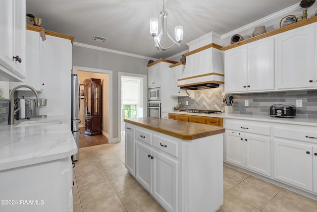 kitchen with appliances with stainless steel finishes, premium range hood, backsplash, light tile patterned floors, and a center island