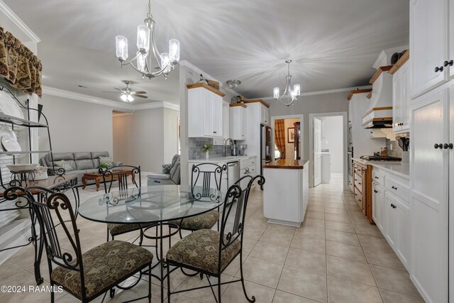 dining space featuring sink, light tile patterned flooring, ceiling fan with notable chandelier, and ornamental molding