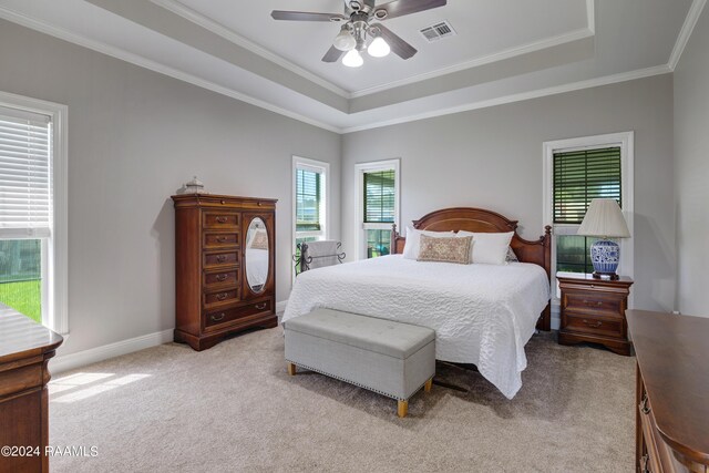 bedroom featuring ceiling fan, a raised ceiling, light carpet, and multiple windows