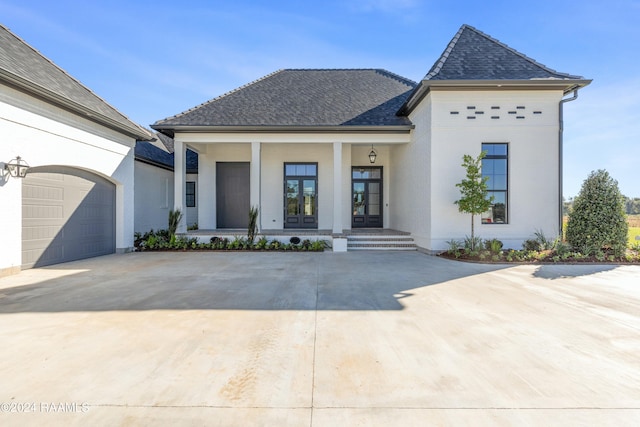 view of front of property with a porch, a garage, and french doors