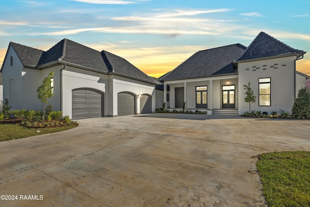 french country style house with a porch and a garage