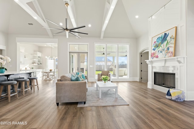 living room featuring high vaulted ceiling, an inviting chandelier, wood-type flooring, and beamed ceiling