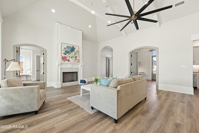 living room with light hardwood / wood-style floors, high vaulted ceiling, and ceiling fan