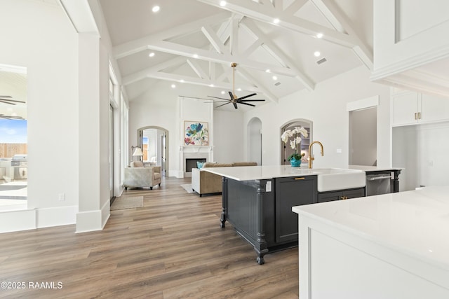 kitchen featuring white cabinetry, a breakfast bar, a large island with sink, ceiling fan, and hardwood / wood-style floors