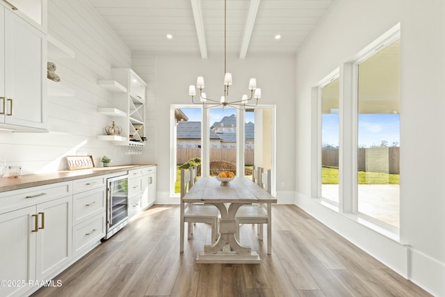 dining area featuring light wood-type flooring, wooden ceiling, beamed ceiling, beverage cooler, and a chandelier