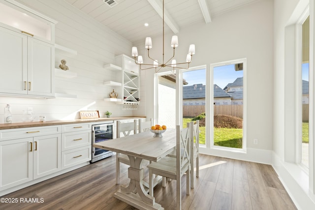 dining room featuring hardwood / wood-style flooring, beamed ceiling, plenty of natural light, and wine cooler