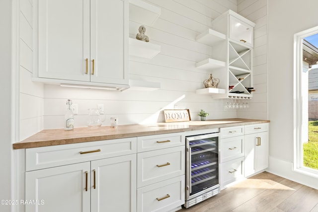 bar featuring wood counters, light hardwood / wood-style floors, white cabinets, and wine cooler