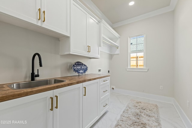 interior space featuring white cabinets, sink, butcher block counters, and ornamental molding