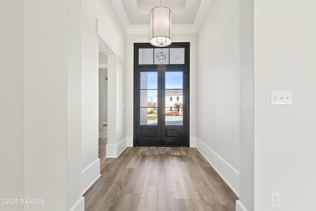 entryway featuring hardwood / wood-style flooring, a tray ceiling, french doors, and ornamental molding