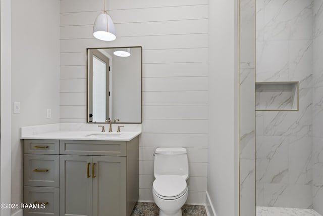 bathroom featuring toilet, vanity, and tiled shower