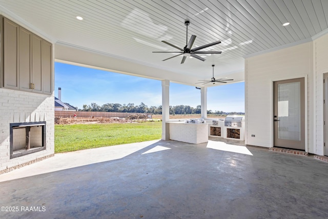 view of patio / terrace featuring an outdoor kitchen, a grill, a rural view, ceiling fan, and an outdoor brick fireplace