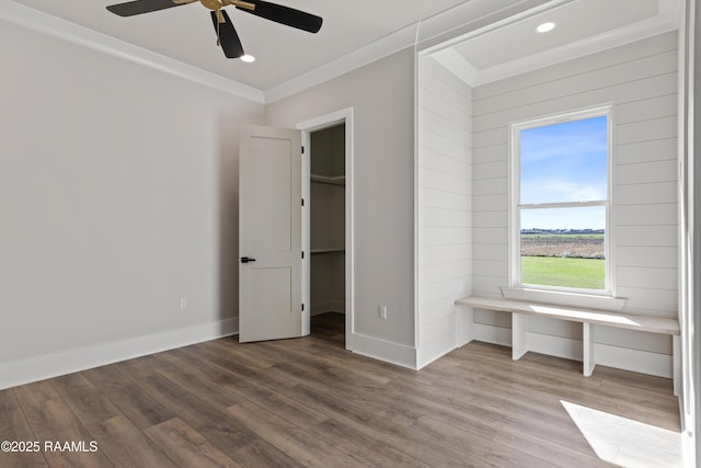 unfurnished bedroom with ceiling fan, hardwood / wood-style flooring, crown molding, and a spacious closet