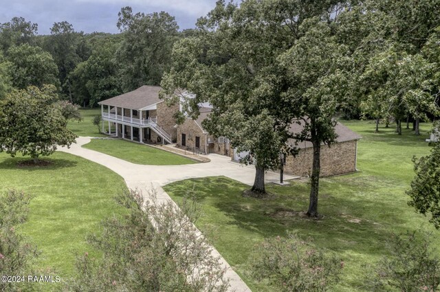 415 Fort Hamilton Dr, Opelousas, LA 70570 - view of home's community featuring a lawn, stairway, a wooded view, and curved driveway