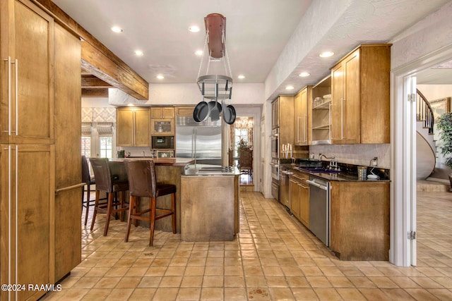 kitchen with light tile patterned floors, built in appliances, sink, and a kitchen island