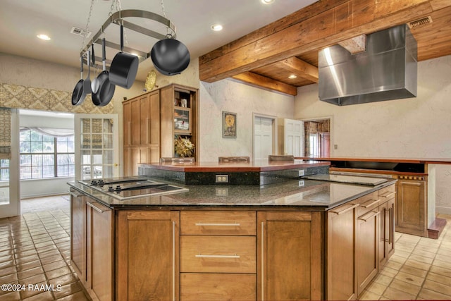 kitchen featuring dark stone counters, beam ceiling, black electric cooktop, light tile patterned floors, and a center island