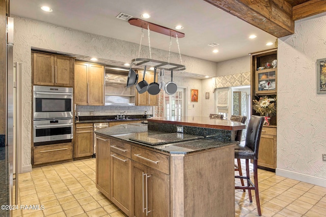 kitchen with a center island, light tile patterned floors, dark stone countertops, and stainless steel appliances