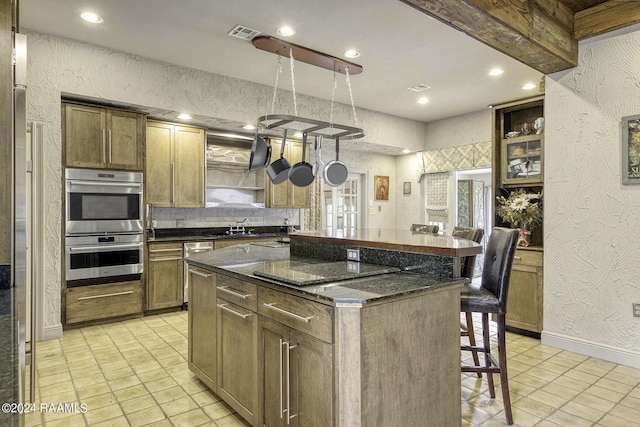 415 Fort Hamilton Dr, Opelousas, LA 70570 - kitchen featuring a breakfast bar, a kitchen island, a textured wall, and double oven
