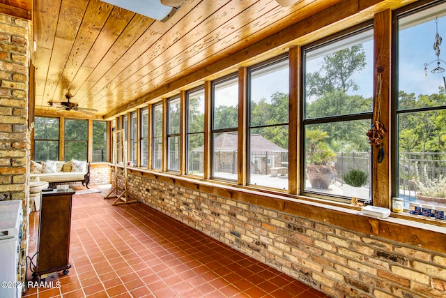 unfurnished sunroom featuring wood ceiling, plenty of natural light, and ceiling fan